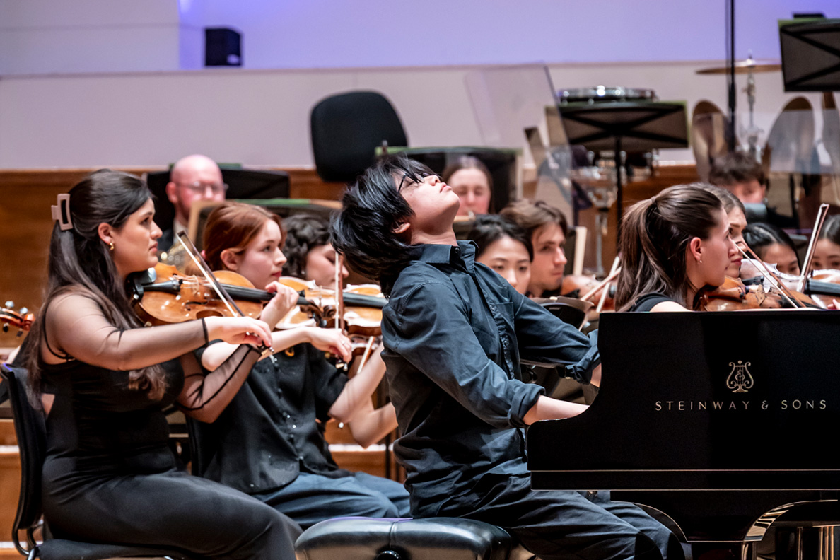 Pianist performing in front of an orchestra at the Royal College of Music.